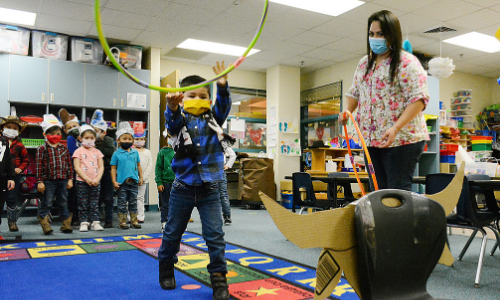 Student throws hula hoop around chair Student throws hula hoop around chair